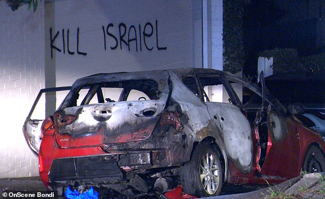 Anti-Semitic graffiti was spray-painted on a wall behind a badly burned car in Woollahra, Sydney's east