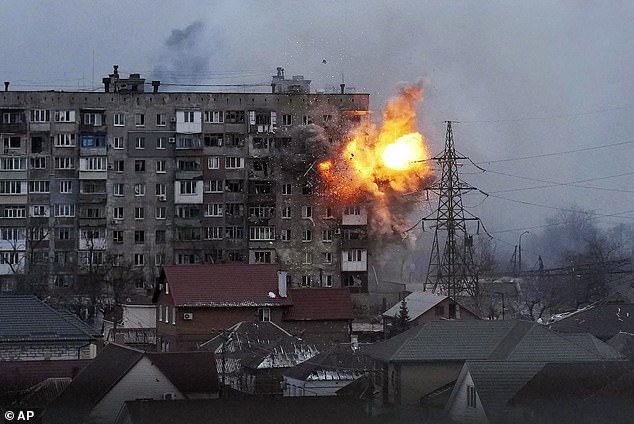 An explosion rocks an apartment building after a Russian army tank fires in Mariupol, Ukraine, Friday, March 11, 2022