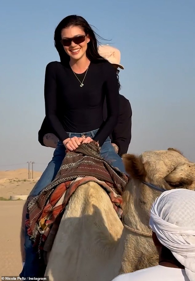 Nicola beamed as she enjoyed a camel ride with her husband Brooklyn sitting behind her