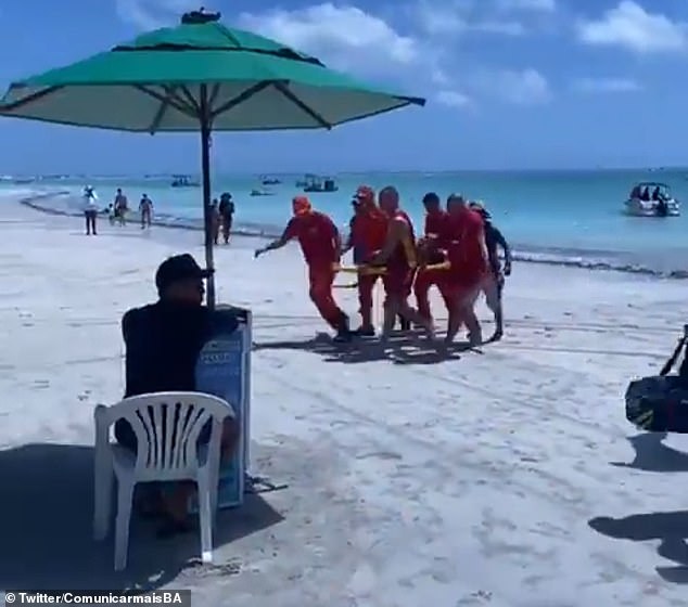 Pictured: First responders with one of the passengers rescued after the catamaran carrying 50 people, including three crew members, sank on a Brazilian beach