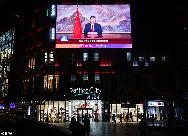 People walk past a screen showing Chinese President Xi Jinping delivering a New Year's message in Beijing, China, December 31, 2024