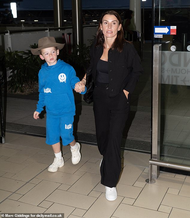 Coleen Rooney's son Cass claimed her I'm A Celebrity hat as she arrived at Brisbane Airport on Tuesday for her trip home