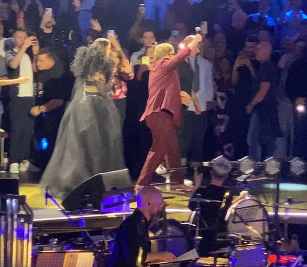 A production assistant extends a supportive hand to the 77-year-old singer as he walked backstage at the Royal Albert Hall on October 17.