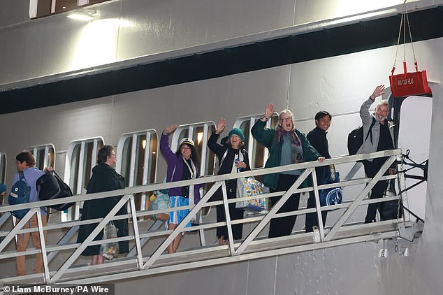 Passengers wave as they board the Villa Vie Odyssey at the Belfast Cruise Ship Terminal on September 30