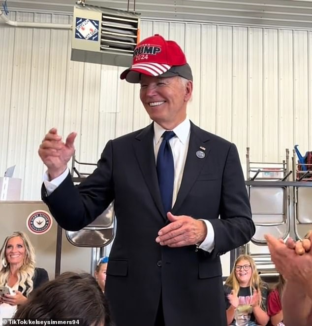 Dr. Jill wakes up to find the President hard at work at his desk, still dressed in his red MAGA nightcap and Trump 2024 onesie. (Image: President Biden wearing a Trump 2024 hat on the campaign trail in September 2024)