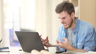 A man gets angry at his laptop.