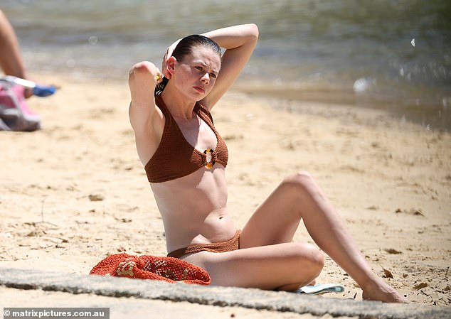 Lucia Hawley, 26, (pictured) set pulses racing on Thursday as she stripped down to a brown bikini to soak up the sun on a Sydney beach