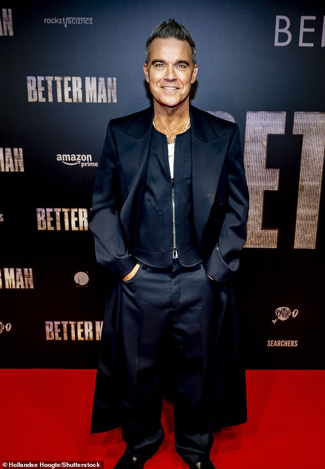 Robbie cut a dapper figure for the evening in a smart navy blue jacket which he teamed with matching trousers and a long coat