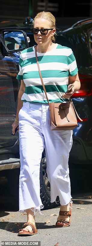 The TV presenter dressed casually for the outing in white trousers and a white and green striped T-shirt as she looked at her phone