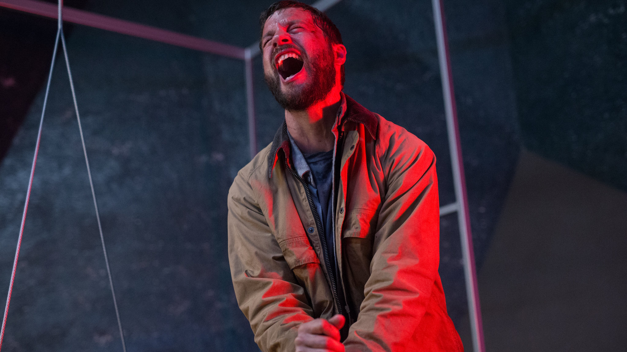 A man bathed in red light and screams in pain in Upgrade.