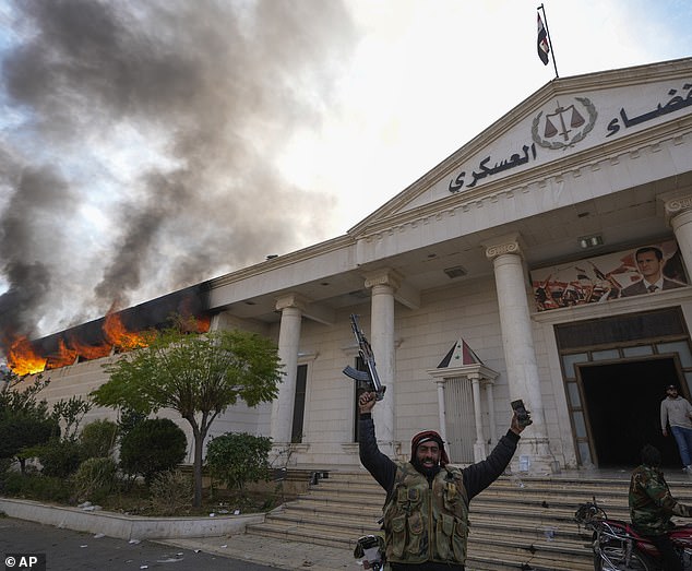 Opposition fighters celebrate as they burn down a military court in Damascus