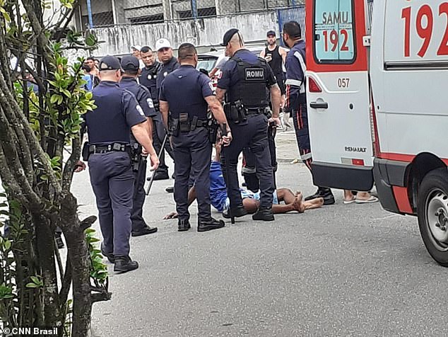 Claudio da Silva is surrounded by officers on Sunday in Praia Grande, a beach resort in the southeastern Brazilian city of São Paulo, moments after he allegedly stole a man's mobile phone and launched a wild chase, caught on camera, which showed he was attacked from behind by an SUV driven by the robbery victim's boyfriend, who also struck and killed a mother and her daughter