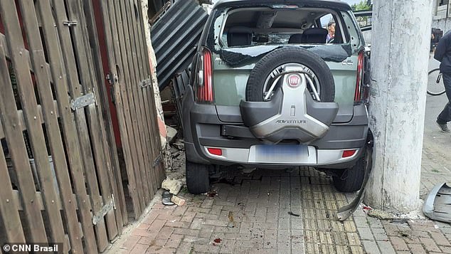 João Barbosa's vehicle became stuck between a light pole and the fence of a home in Praia Grande, Brazil, on Sunday after he jumped the sidewalk after hitting a robbery suspect on a bicycle and into a mother and daughter who were riding their own bicycles. the sidewalk