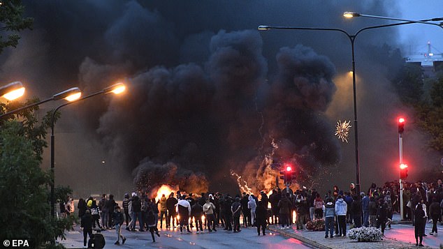 Smoke rises from burning tires, pallets and fireworks during police riots with a few hundred protesters in the Rosengard district of Malmö, Sweden, August 28, 2020