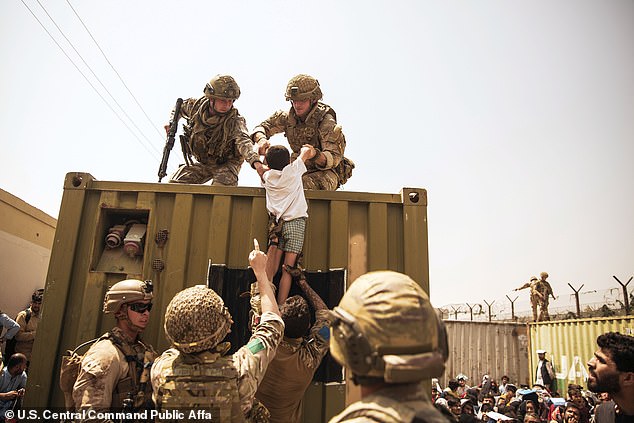 U.S. Marines help a child to safety during the 2021 evacuation at Hamid Karzai International Airport after the Taliban invaded the city in August that year