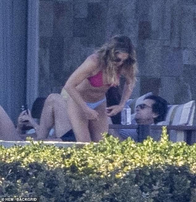 The 55-year-old showed off her flat midriff in her coral triangle bikini top, paired with blue swim trunks