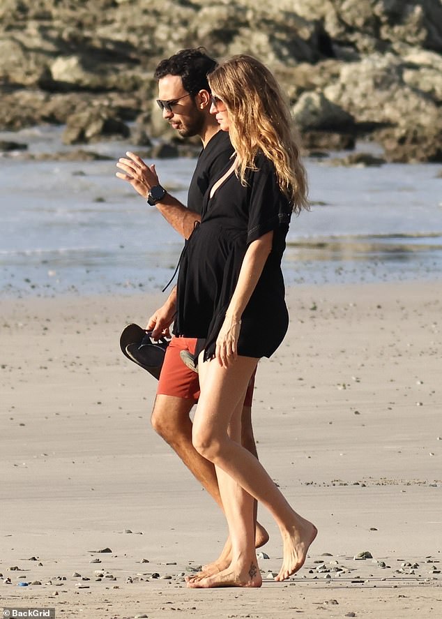 Gisele showed off her bump in a low-cut, flowing black mini dress