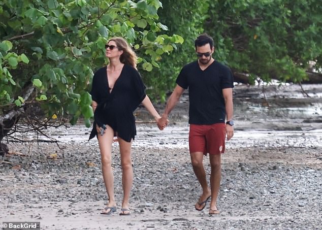 The model and jiu-jitsu instructor held hands as they walked along the beach with their dog ahead of the New Year