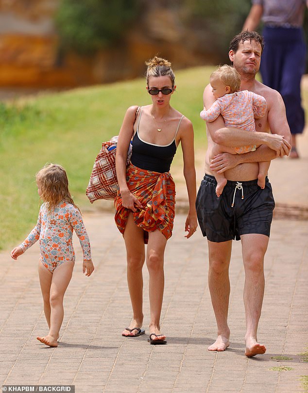 The veteran journalist, 41, showed off his muscular physique in black swim trunks as he strolled barefoot along the sandy paths