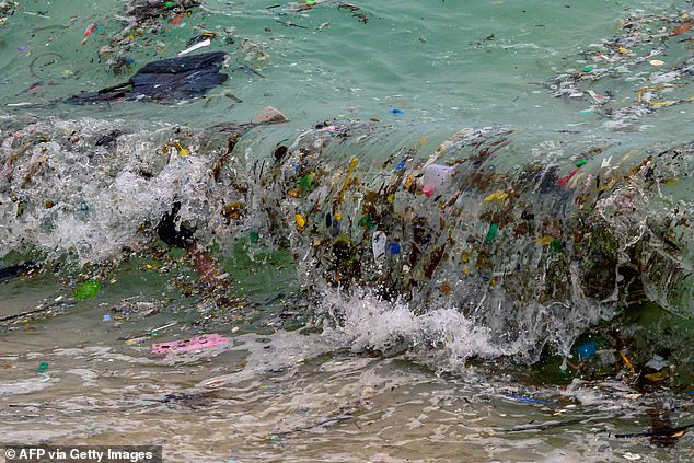 A wave of plastic waste and other waste washes up on a beach in Koh Samui