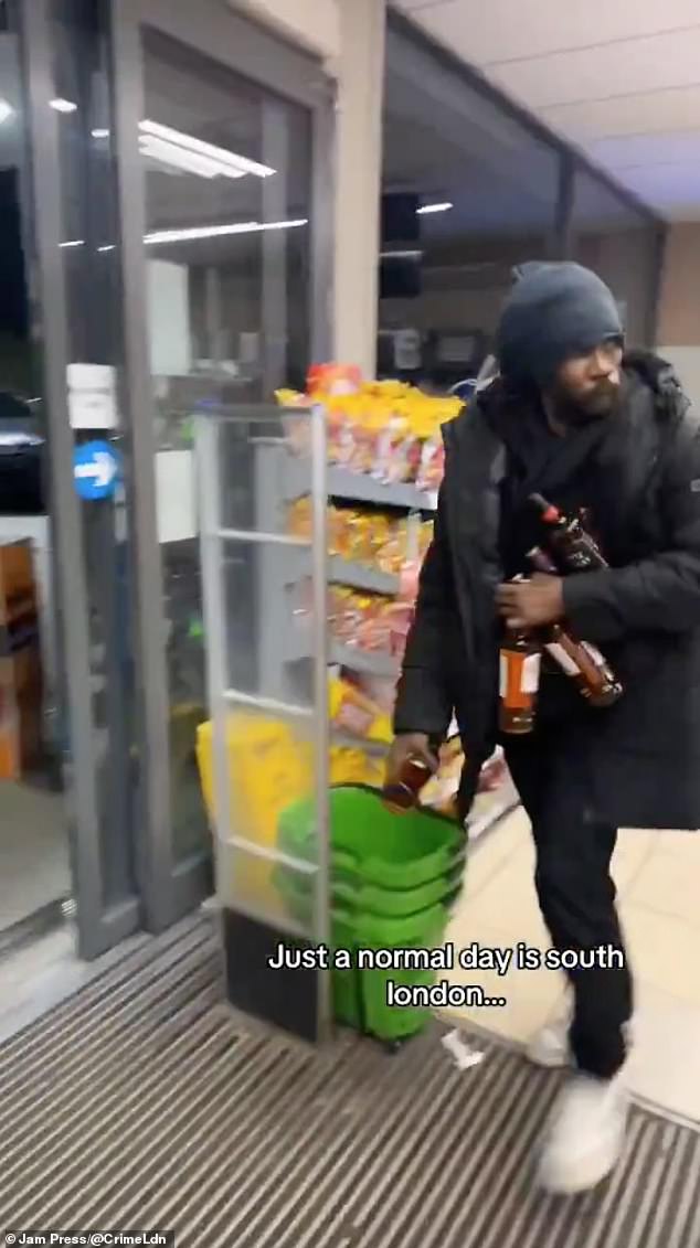 Another thief is seen taking several bottles during the robbery of the Asda Express at the Texaco garage on Wandsworth Road, Battersea, South London