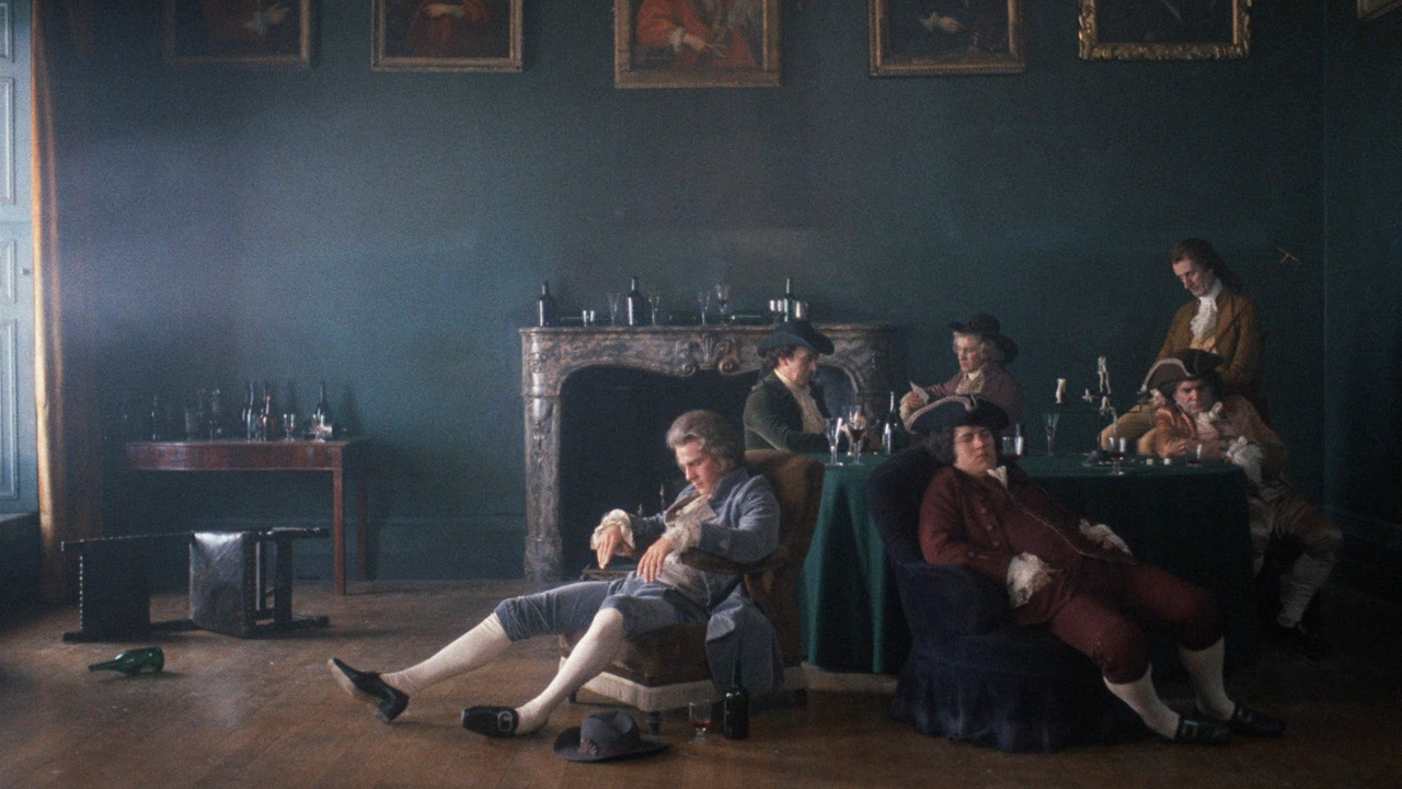 A man in a powdered wig sitting in a saloon surrounded by empty bottles of alcohol and several other drunken men in Barry Lyndon.