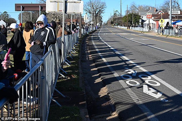 People line the street in Plains, Georgia, before the hearse carrying former President Jimmy Carter's casket drives through town