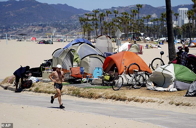 A jogger runs past a homeless encampment in Los Angeles' Venice Beach neighborhood, which is beginning to make gains against the scourge