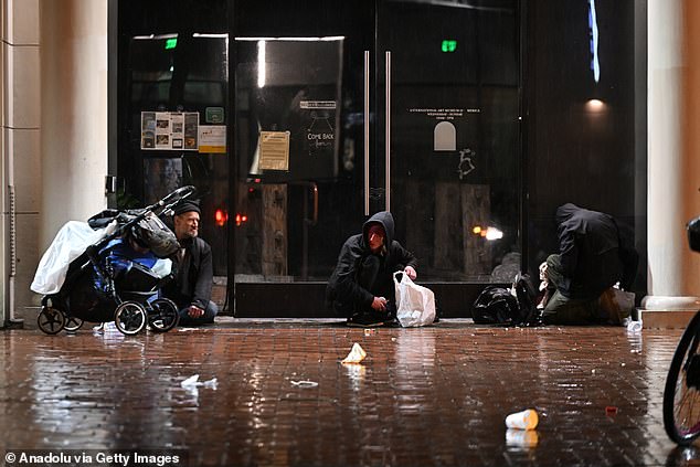 Homeless people are seen near City Hall during heavy rain in San Francisco, California