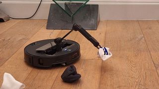 Roborock Saros Z70 robot vacuum cleaner that picks up a sock with its pincer arm