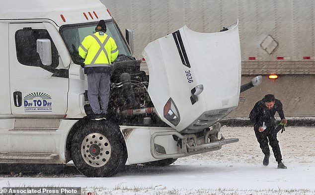 Truck drivers battle the weather as they stop on Interstate 44 in Fenton, Missouri to replace windshield wiper blades as sleet falls on Sunday (Cohen/St. Louis Post-Dispatch via AP)