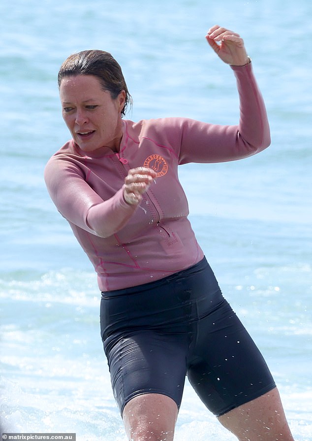 The television journalist put on a light pink and black wetsuit and jumped on her blue board