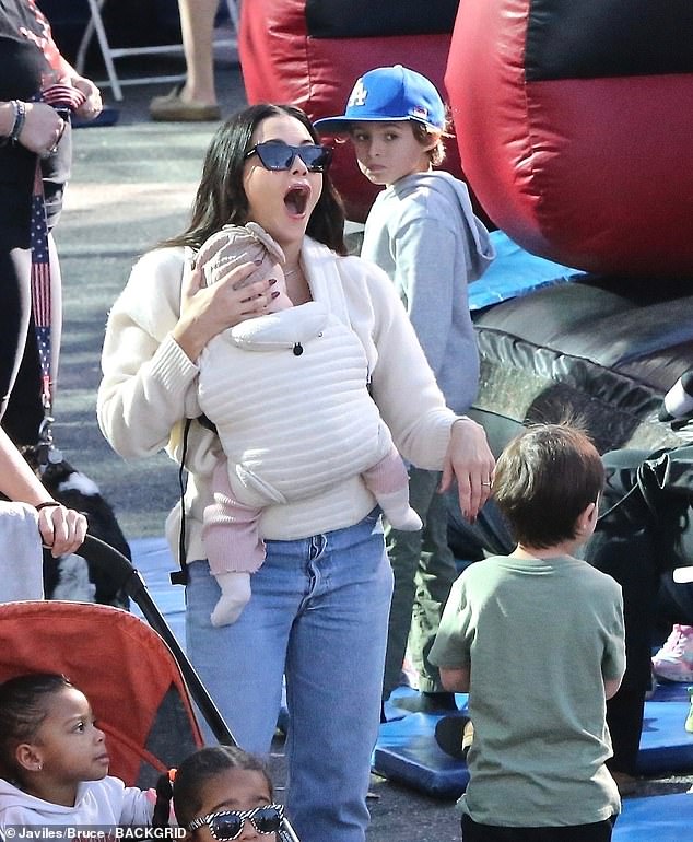 The doting mum held Rhiannon close in a cream-coloured baby carrier, with her chubby legs covered in pink trousers and her tiny feet covered in white socks