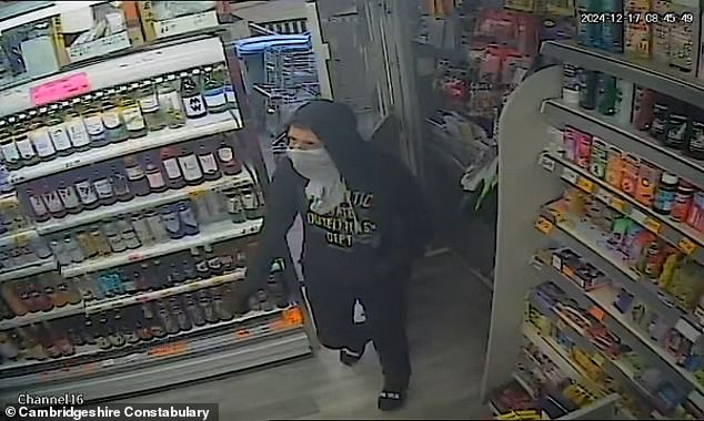 Bizarre footage captured the moment a customer casually pushed aside the yob balaclava so he could pay for his item. This image shows the man entering the store in Peterborough, Cambridgeshire