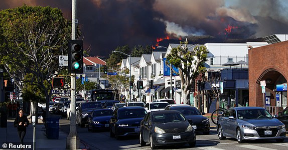 People evacuate as smoke rises from a wildfire burning near Pacific Palisades on the west side of Los Angeles during a weather-related storm, in Los Angeles, California, January 7, 2025. REUTERS/Daniel Cole TPX IMAGES OF THE DAY