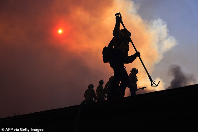 Firefighters are seen working diligently as LA residents rush to leave the wealthy neighborhood