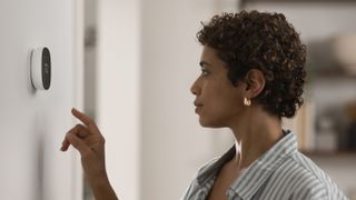 Woman using Ecobee Smart Thermostat Essential installed on the wall