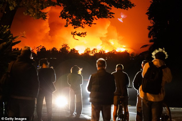 People watch the smoke and flames from the Palisades Fire in the Pacific Palisades neighborhood on January 7