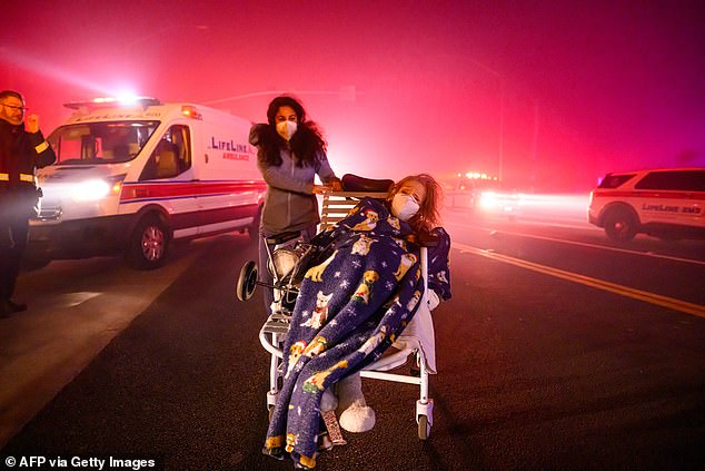 Elderly patients are quickly evacuated into emergency vehicles as embers and flames approach during the Eaton fire in Pasadena, California on January 7