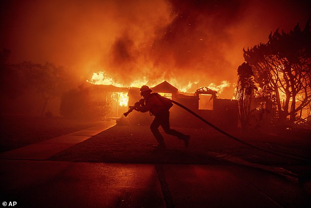 A firefighter battles the Palisades Fire as it burns a building in the Pacific Palisades neighborhood of Los Angeles