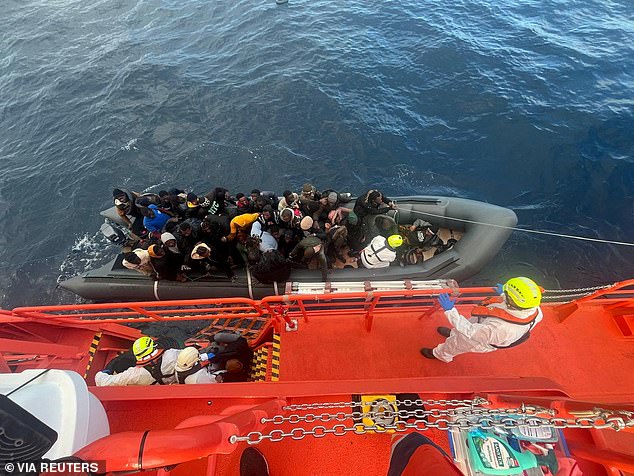 Spanish coastguards, dressed in white suits, work a rescue operation as they tow a rubber boat carrying migrants, including a newborn baby, from the Canary Island of Lanzarote in Spain, in this handout photo obtained on January 8, 2025