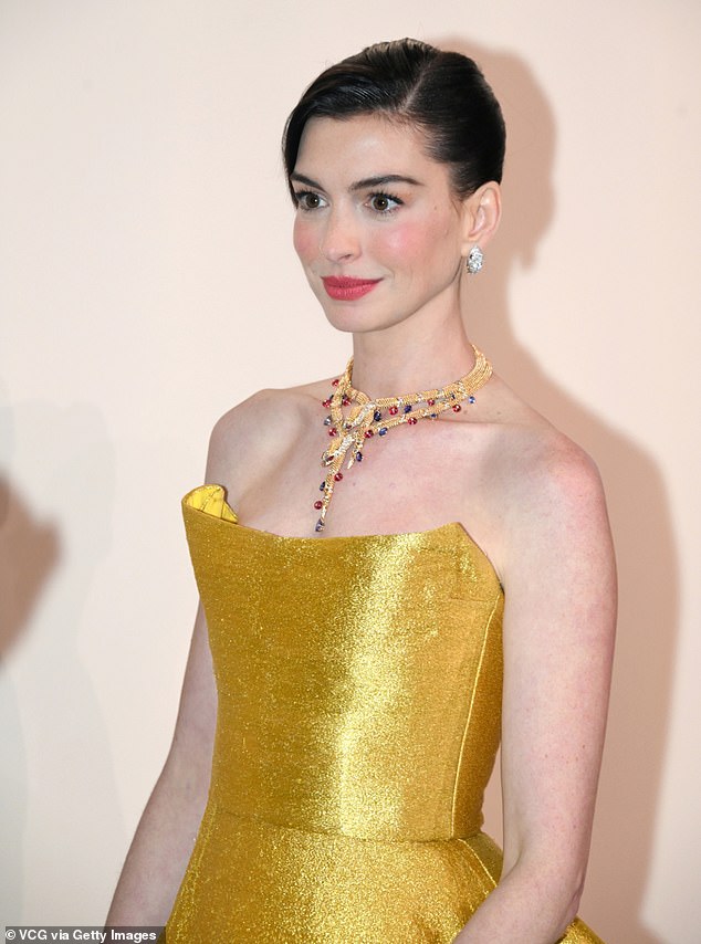 Anne accessorized her shiny dress with a gold necklace with colorful jewels and silver statement earrings