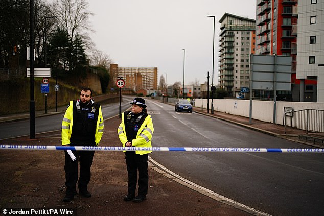 Two police officers stand outside a police cordon on Woolwich Church Road where the teenager was stabbed to death on Tuesday