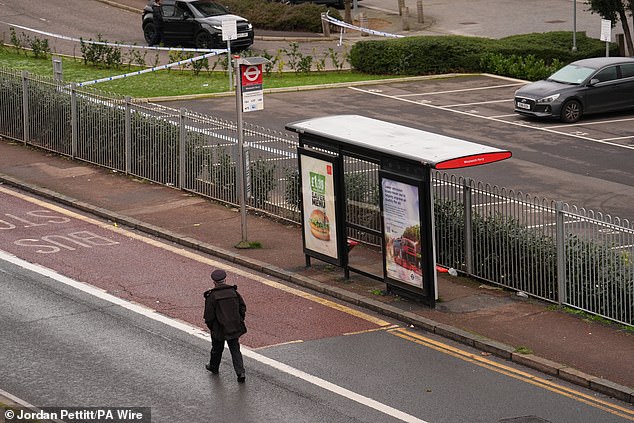 A police officer walks past a bus stop on Woolwich Church Road in Woolwich after a 14-year-old boy was stabbed to death on a bus