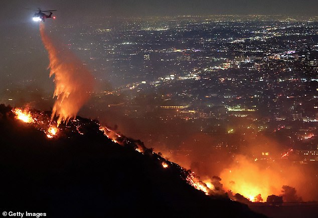 A firefighting helicopter drops water as the Sunset Fire burns in the Hollywood Hills