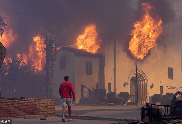 A man walks in front of the burning Altadena Community Church, Wednesday, January 8, 2025, in Pasadena, California