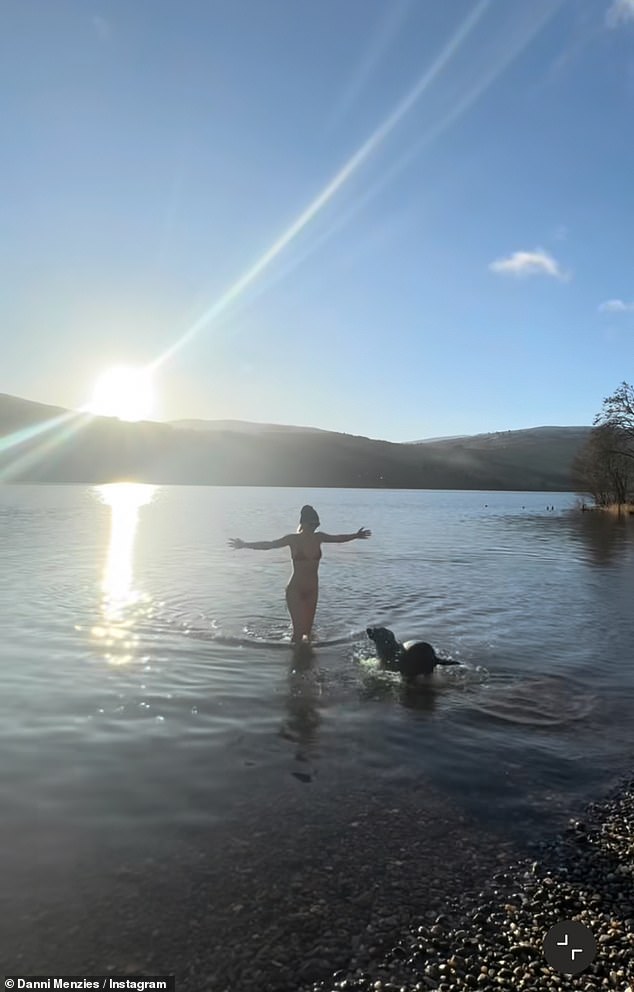 The star, who has spoken about her love of wild swimming, then steps into the water and wades out before being joined by her black Labrador Mona, who swims towards her.