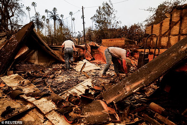 People are seen searching for the remains of a house that burned down in Altadena