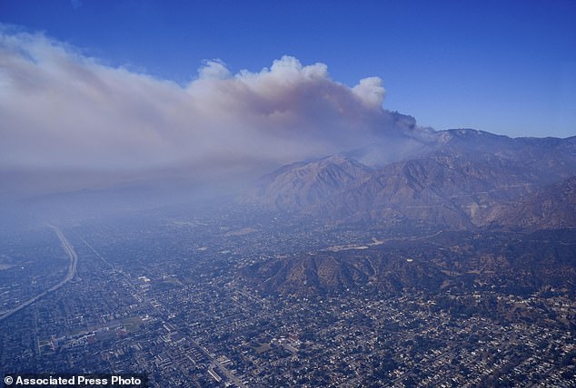 A plume of smoke from a wildfire forms over the Los Angeles city basin on Thursday