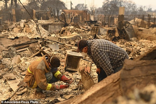 Robert Lara, left, searches for belongings with his stepfather after the Eaton Fire burns in Altadena, California